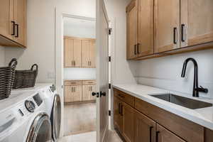 Washroom featuring separate washer and dryer, cabinets, light hardwood / wood-style floors, and sink