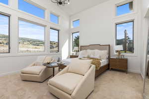 Bedroom with light colored carpet, high vaulted ceiling, and multiple windows