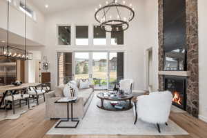 Living room with high vaulted ceiling, light wood-type flooring, and a stone fireplace