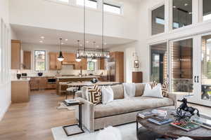 Living room featuring light hardwood / wood-style flooring, a towering ceiling, sink, and a chandelier