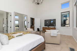 Bedroom featuring an inviting chandelier, light carpet, and a towering ceiling