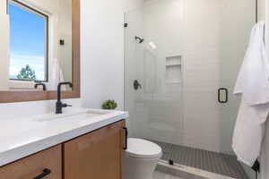 Bathroom with tile patterned flooring, vanity, a shower with shower door, and toilet