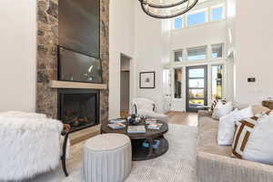 Living room with light hardwood / wood-style flooring, a high ceiling, a chandelier, and a fireplace