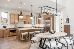 Kitchen with hanging light fixtures, a center island, light hardwood / wood-style flooring, and stainless steel appliances