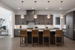 Kitchen featuring a kitchen breakfast bar, a center island with sink, sink, and pendant lighting