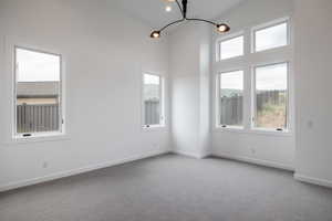 Carpeted empty room featuring a wealth of natural light and a chandelier