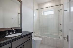 Full bathroom with vanity, toilet, tiled shower / bath combo, and tile patterned floors