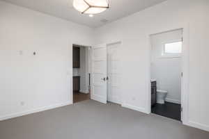 Unfurnished bedroom featuring ensuite bath and carpet floors