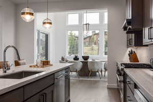 Kitchen featuring dishwashing machine, stainless steel gas stove, sink, dark hardwood / wood-style floors, and pendant lighting