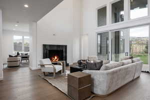 Living room featuring hardwood / wood-style floors, a high ceiling, and a large fireplace