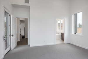 Unfurnished bedroom with ensuite bathroom and carpet floors