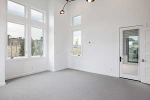 Carpeted empty room featuring a towering ceiling and a healthy amount of sunlight