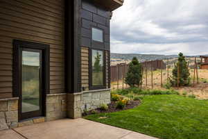 View of property exterior featuring a mountain view, a lawn, and a patio area