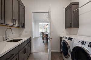 Laundry area featuring washer and dryer, cabinets, sink, and light wood-type flooring