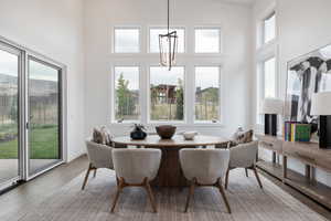 Dining space with a wealth of natural light, high vaulted ceiling, and hardwood / wood-style flooring