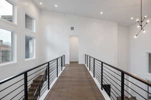 Corridor with high vaulted ceiling, an inviting chandelier, and dark hardwood / wood-style floors