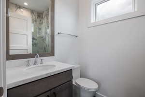 Bathroom featuring vanity, toilet, a wealth of natural light, and tiled shower