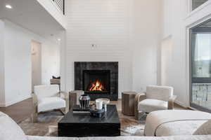 Living room featuring a fireplace, a towering ceiling, and hardwood / wood-style flooring