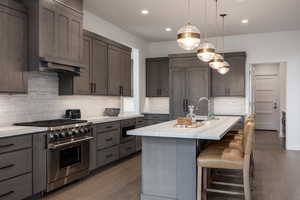 Kitchen with hardwood / wood-style floors, a kitchen bar, stainless steel appliances, and a center island with sink