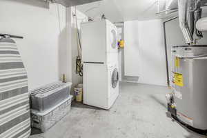 Laundry room with gas water heater and stacked wash/dryer