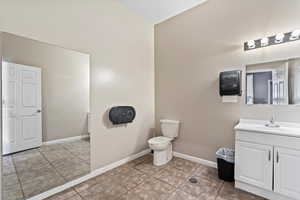 Bathroom 1 featuring paper towel dispenser, sink, toilet, and tile floors w/floor drain