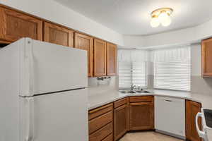 Kitchen featuring backsplash, light tile patterned floors, white appliances, sink, and a textured ceiling