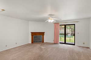 Unfurnished living room featuring ceiling fan, light carpet, and a textured ceiling