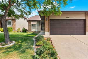 Ranch-style house featuring a garage and a front lawn