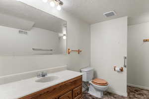 Bathroom featuring vanity, toilet, and a textured ceiling