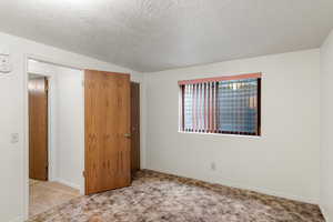 Unfurnished bedroom with a textured ceiling and light carpet