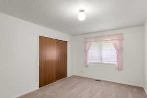 Unfurnished bedroom with a closet, carpet, and a textured ceiling