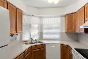 Kitchen featuring white appliances, sink, and tasteful backsplash