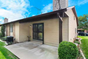 Rear view of property with a yard, central AC unit, and a patio