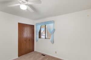 Carpeted bedroom featuring a textured ceiling, ceiling fan, and a closet