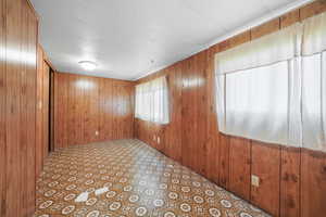 Unfurnished room featuring wooden walls