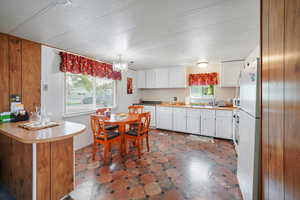 Kitchen featuring a textured ceiling, sink, a chandelier, and white cabinets