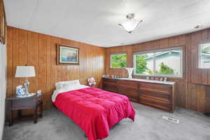 Carpeted bedroom featuring wooden walls