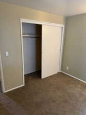 Unfurnished bedroom with dark colored carpet and a closet