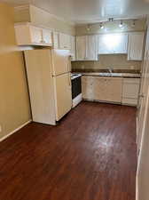 Kitchen featuring track lighting, white appliances, dark hardwood / wood-style flooring, and sink