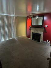 Unfurnished living room with carpet flooring and a tile fireplace