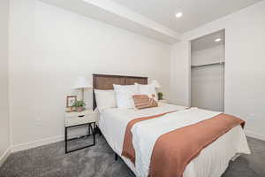 Bedroom featuring a closet, a spacious closet, and dark colored carpet