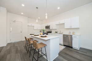 Kitchen featuring dark hardwood / wood-style flooring, white cabinetry, a center island, and stainless steel appliances