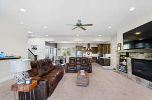 Living room featuring ceiling fan, light carpet, and a fireplace