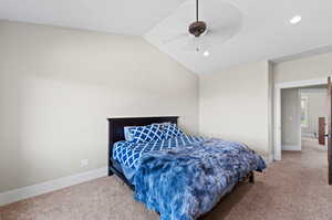 Carpeted bedroom featuring vaulted ceiling and ceiling fan