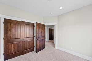 Unfurnished bedroom featuring a closet and light carpet