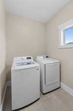 Laundry area with light tile patterned flooring and washing machine and dryer