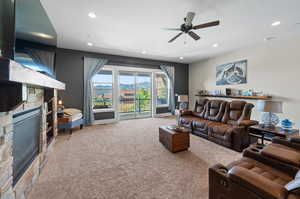 Living room featuring ceiling fan, a fireplace, and carpet floors