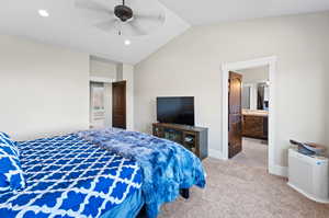 Carpeted bedroom with ensuite bath, vaulted ceiling, and ceiling fan