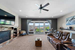 Living room featuring a fireplace, ceiling fan, and carpet flooring