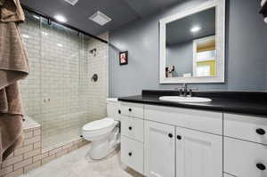 Bathroom featuring vanity, toilet, tiled shower with built in seat, large mirror, and tile patterned flooring